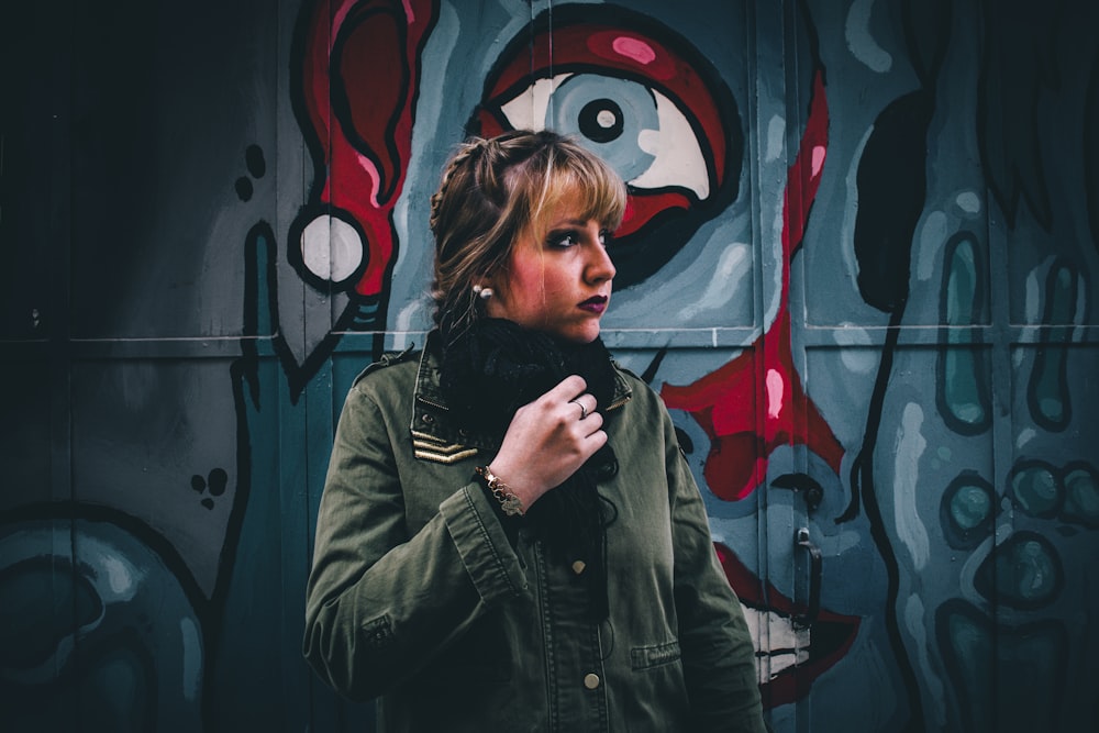 woman in green coat near graffiti