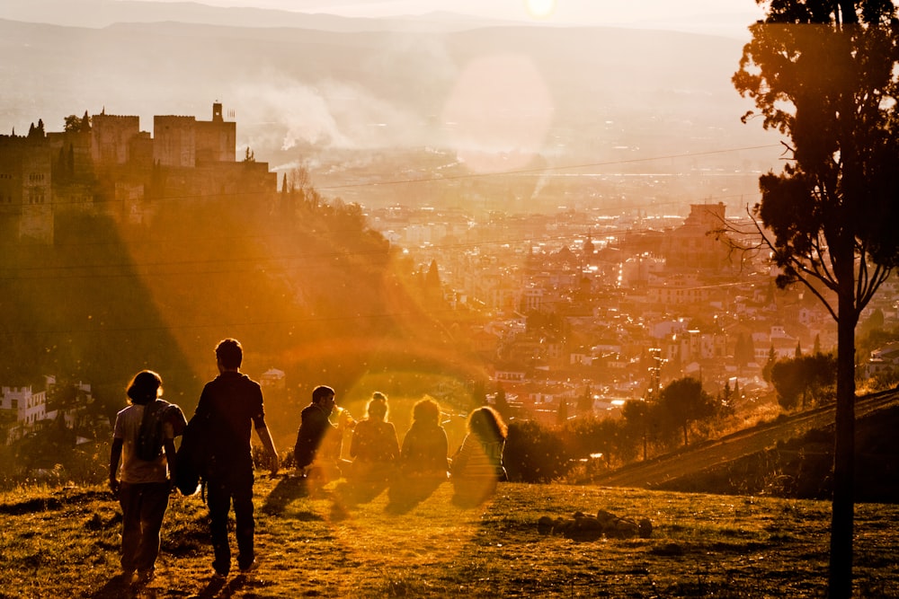 Groep mensen die met zonsondergang op bergen zit 