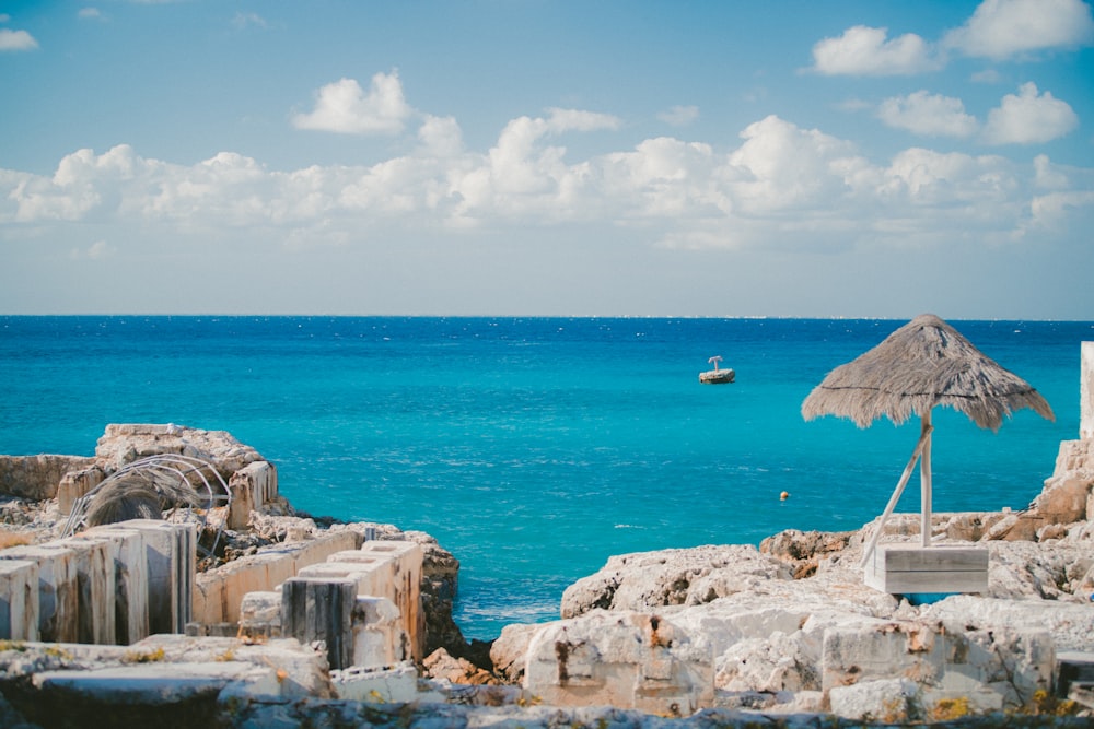 thatch parasol near ruins on island and sea at the distance during day