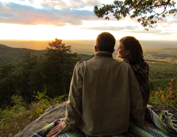 A couple enjoying a scenic sunset view from a mountain overlook during their tour.