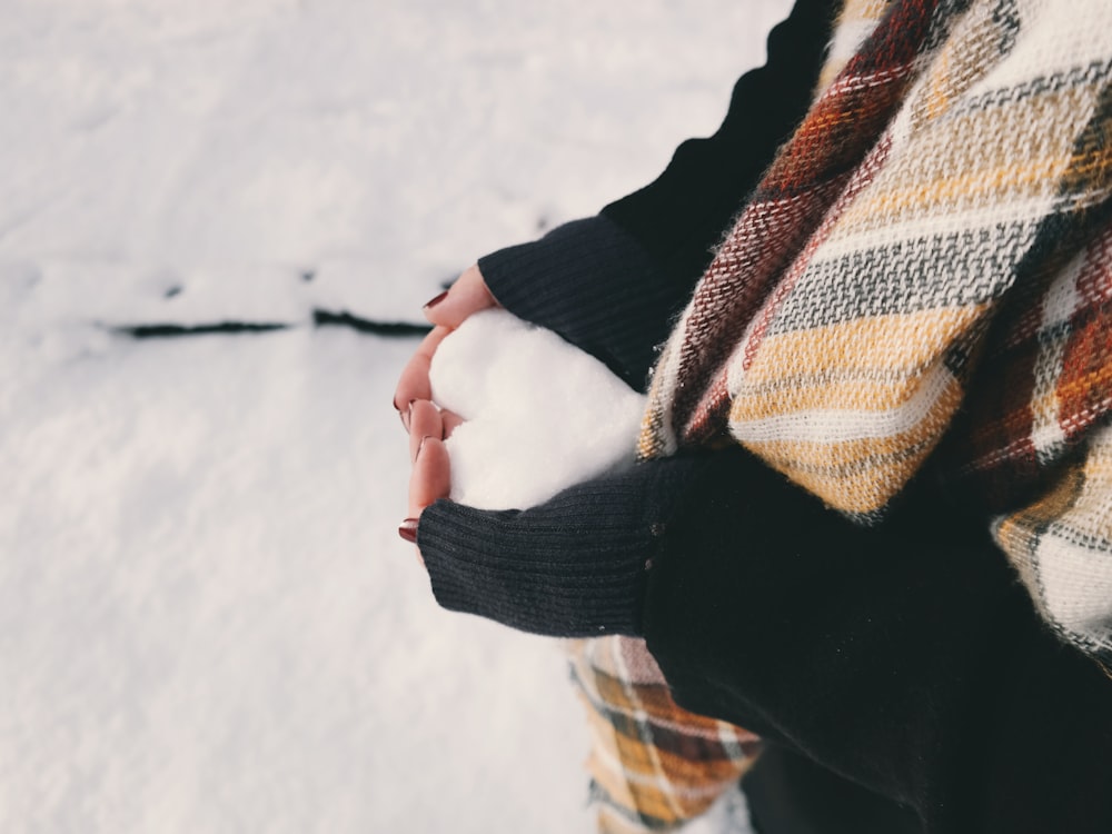 Frau trägt schwarzen Pullover und hält ein eisbildendes Herz