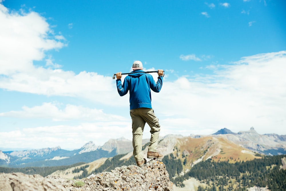 uomo che tiene la barra sulla cima della montagna durante il giorno