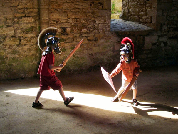 Children dressed as knights and princesses painting shields in a medieval-themed workshop