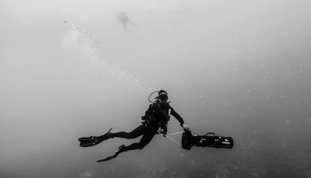 greyscale photo of man wearing spring suit underwater photo