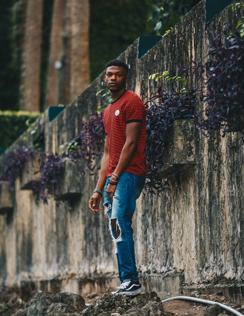 Un hombre afroamericano con jeans rotos y una camisa a rayas rojas.
