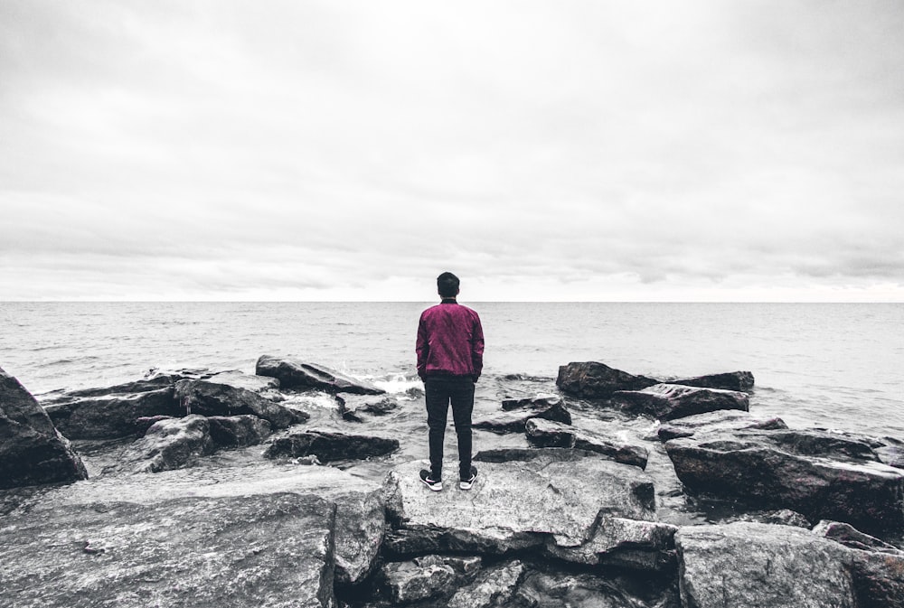 a person standing on a rock near the ocean