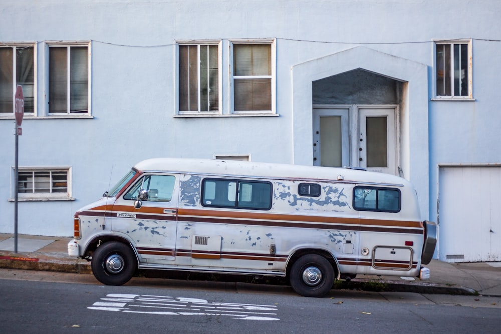 white and brown RV parked on inclined road near white concrete floor in front of red signage