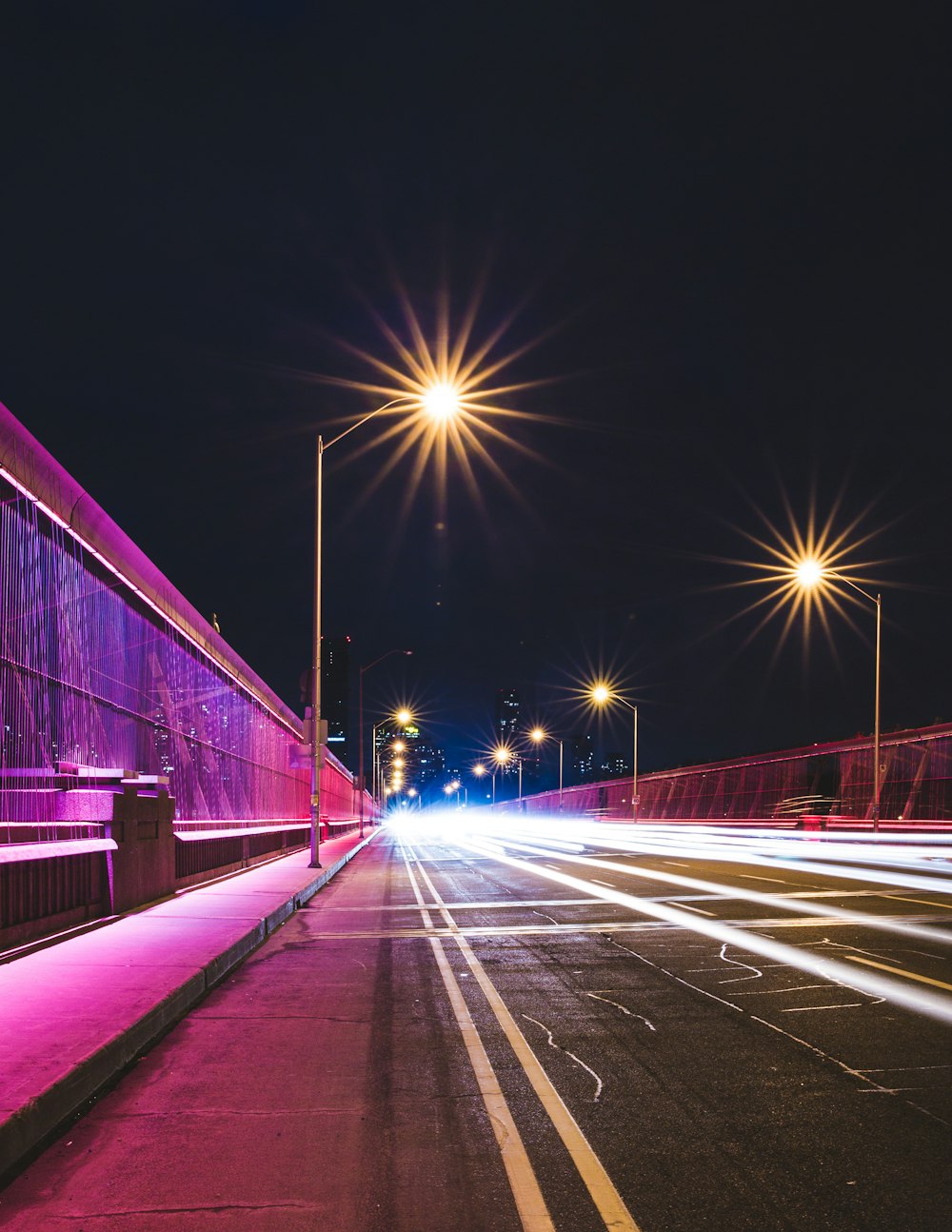 Schwarze Betonstraße zwischen Pfostenlampen unter schwarzem Himmel bei Nacht