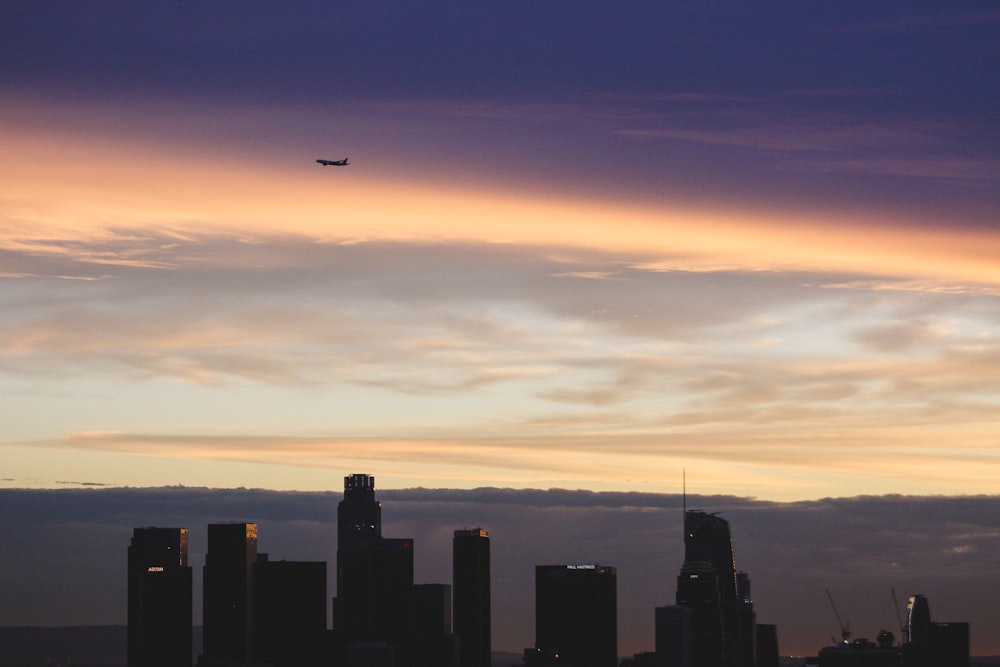 plane flying over silhouette of buildings