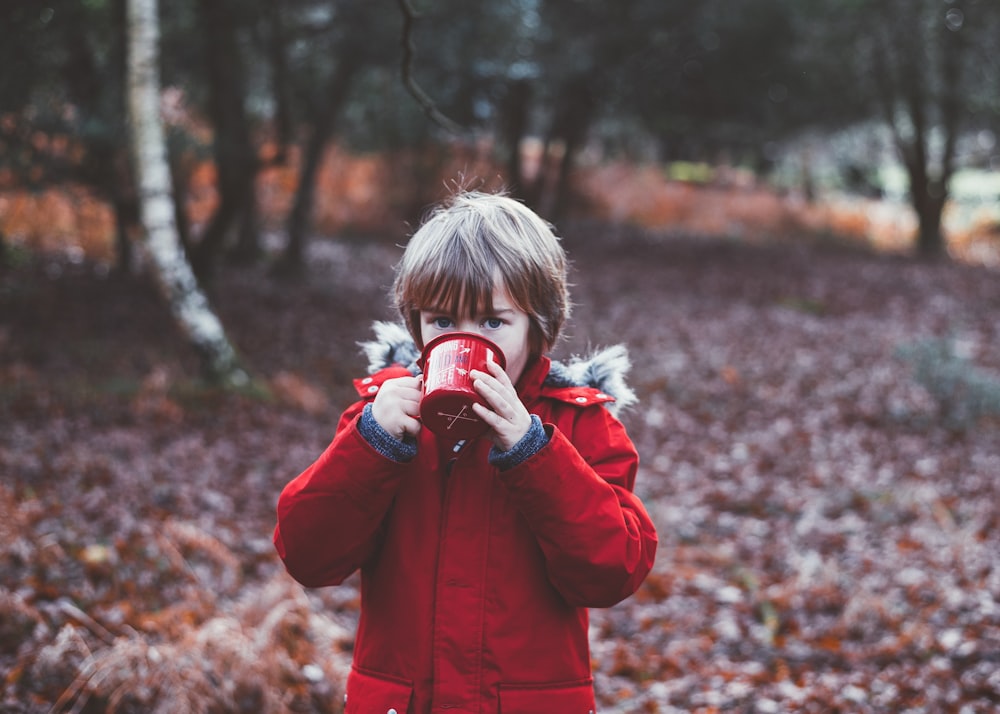 Foto di un bambino che beve usando la tazza all'aperto durante il giorno