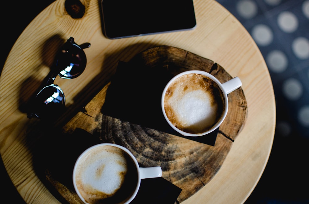 two ceramic cups with cafe latte on wooden table