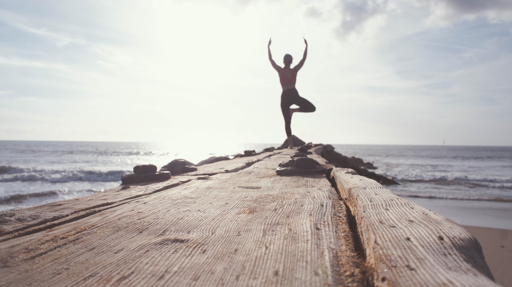 man standing while raising his hands at seashore