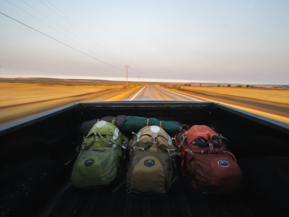 A view from the inside of a cargo area of a pickup truck with three backpacks in it