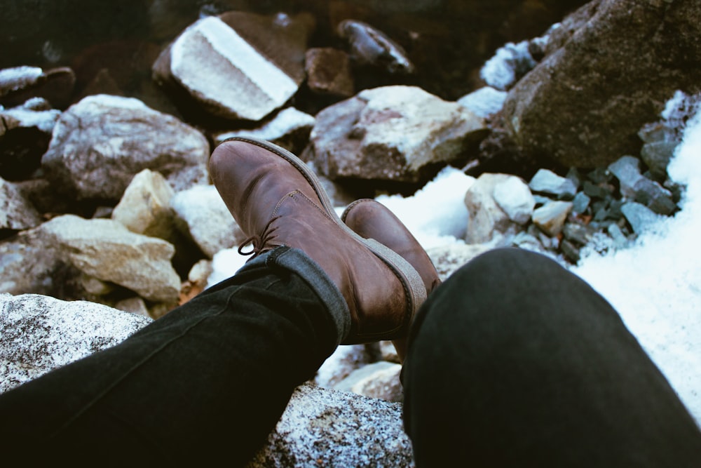 A person sitting and resting their shoes on top of rocks on a snow covered mountain next to Newfound Lake.