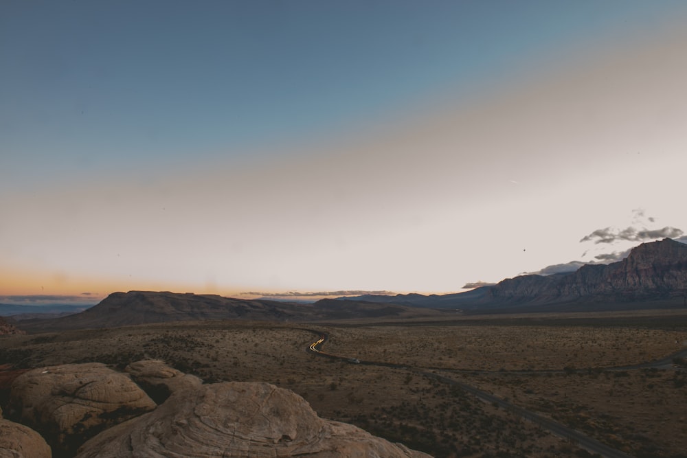 arroyo entre la tierra con montañas marrones a distancia bajo el cielo nublado gris y azul