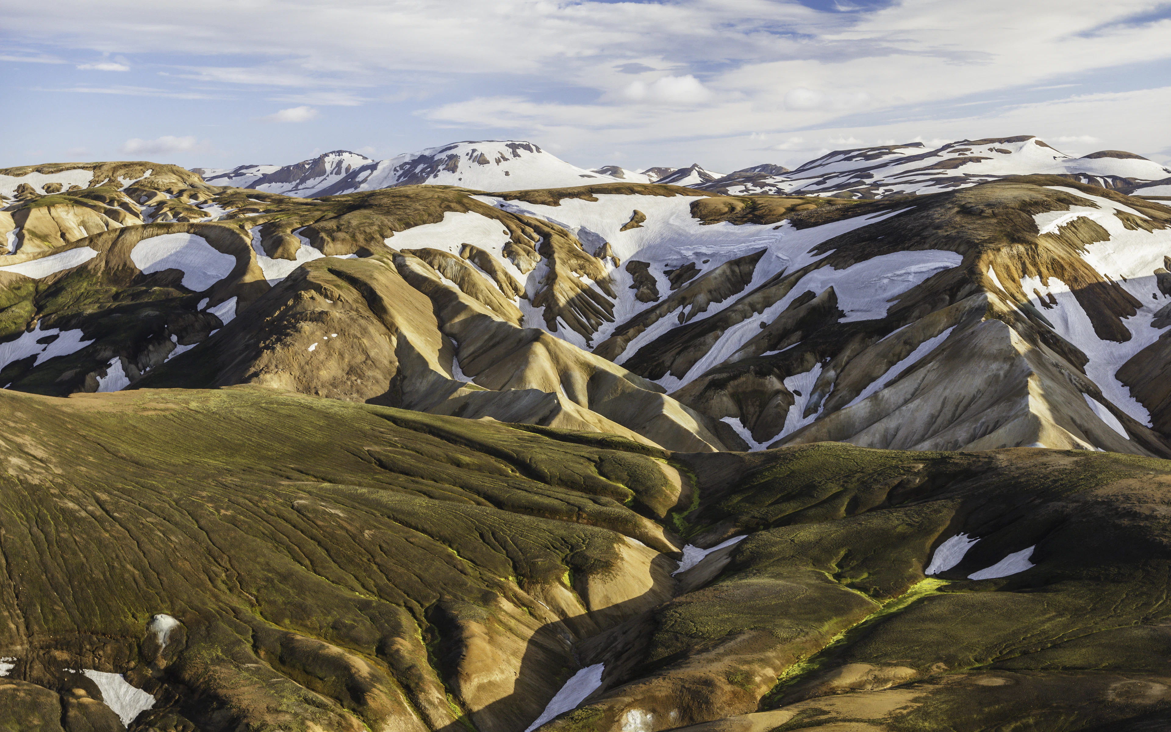 Pink and golden rhyolite hills streaked with the last of the snow on the Laugavegur trail in the Icelandic Highlands