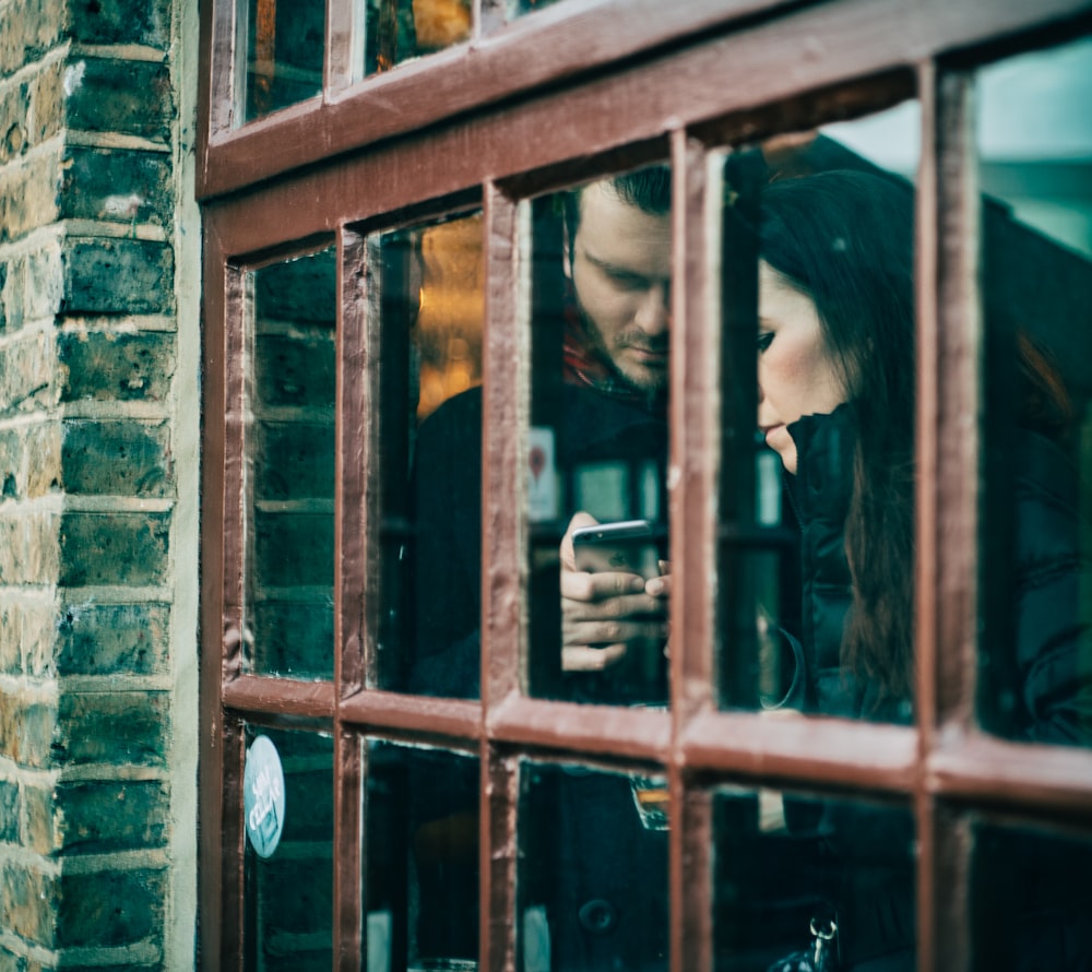 hombre sosteniendo un teléfono inteligente junto a una mujer durante el día