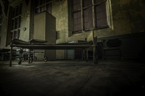 Interior of an abandoned hospital room with peeling paint and old medical equipment.