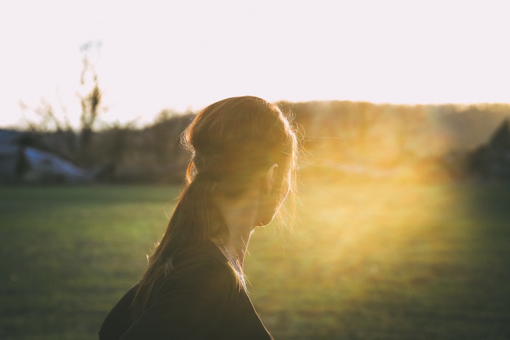 Mujer en top negro mirando hacia el sol durante el día