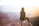 person sitting on top of gray rock overlooking mountain during daytime