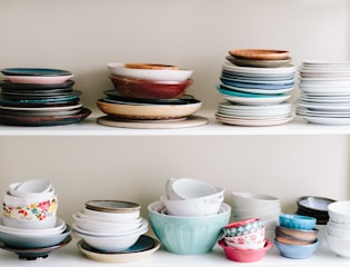 A set of colorful ceramic plates stacked neatly on a rustic kitchen shelf.