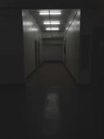 A pixel art hallway with flickering lights and unsettling shadows cast on the walls.