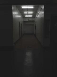 A pixel art hallway with flickering lights and unsettling shadows cast on the walls.