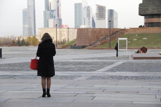 Close-up of a sleek urbanluxe handbag resting on a city bench with skyscrapers blurred in the background.