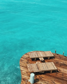 Guests lounging on a wooden deck overlooking crystal-clear waters, with snorkeling gear nearby.