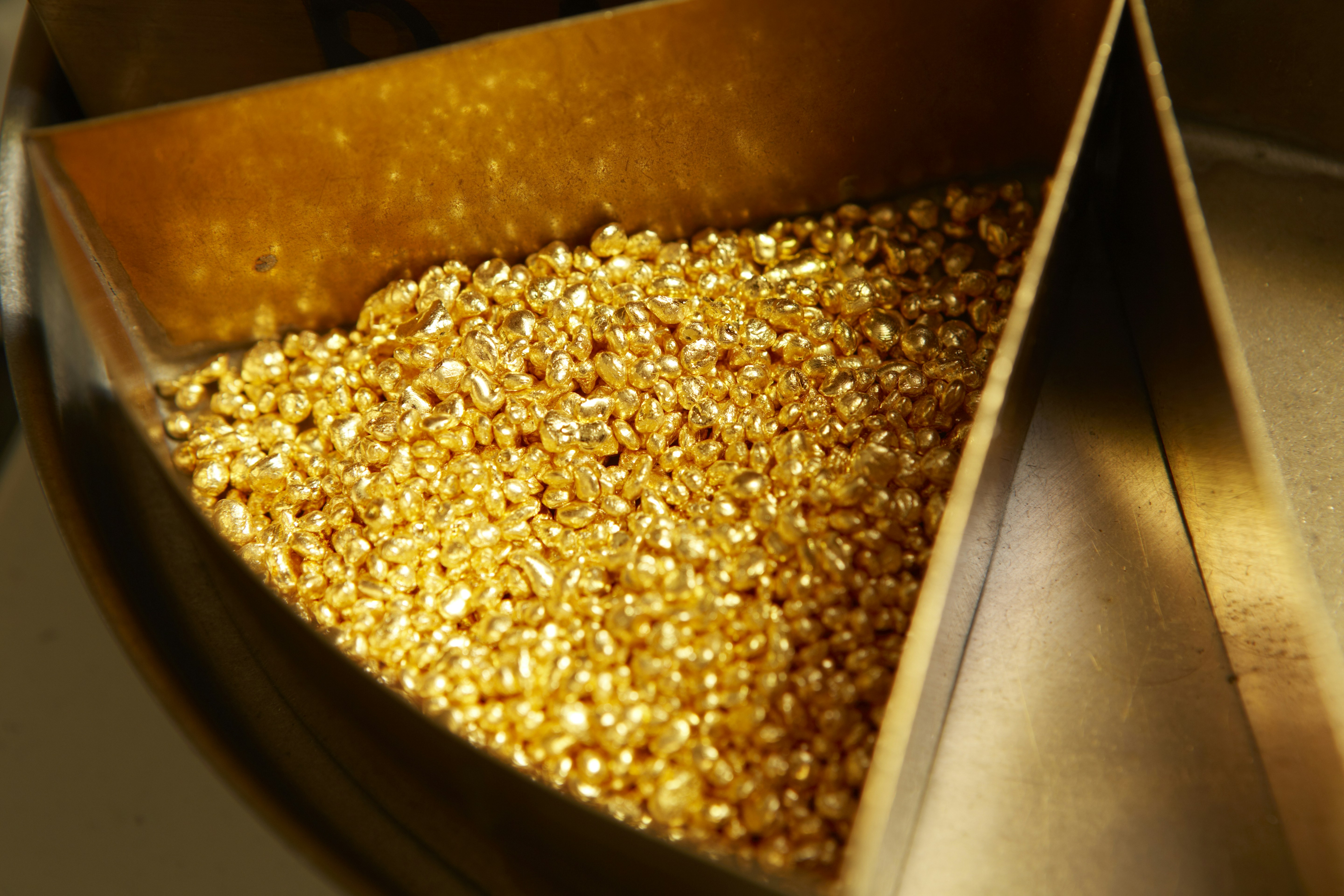 Raw gold nuggets close-up pile, warm golden color mineral photography