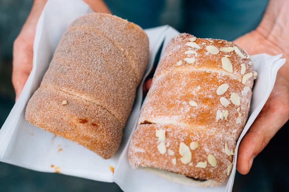 Hands hold two loaves of freshly baked sweet bread