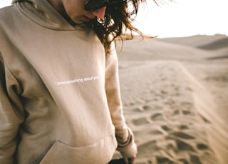 person wearing sunglasses and hoodie on sand