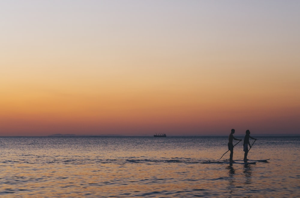 two person kayaked on ocean during golden hour