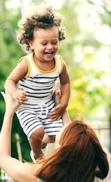 selective focus photo of woman lifting child during daytime