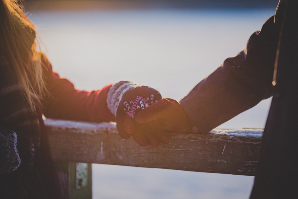 On a winter's day, young lovers hands touch on a cabin railing