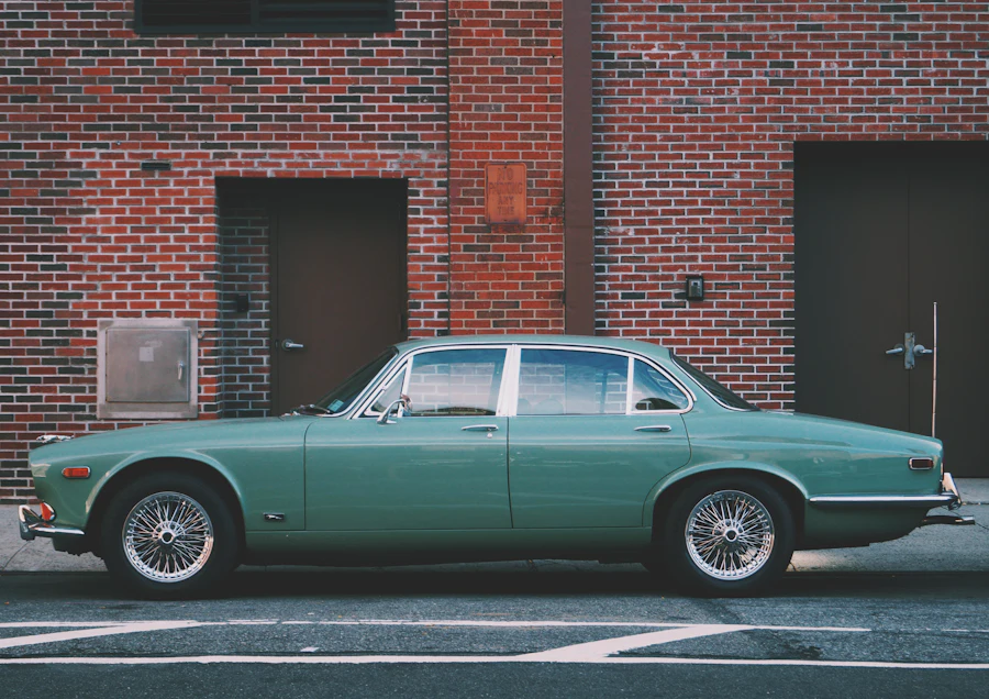 A green classic saloon parked along a brick wall