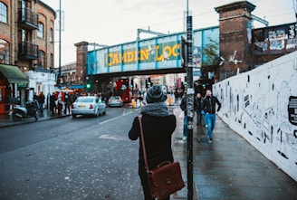 people walking on black concrete road beside buildings under white sky during daytime