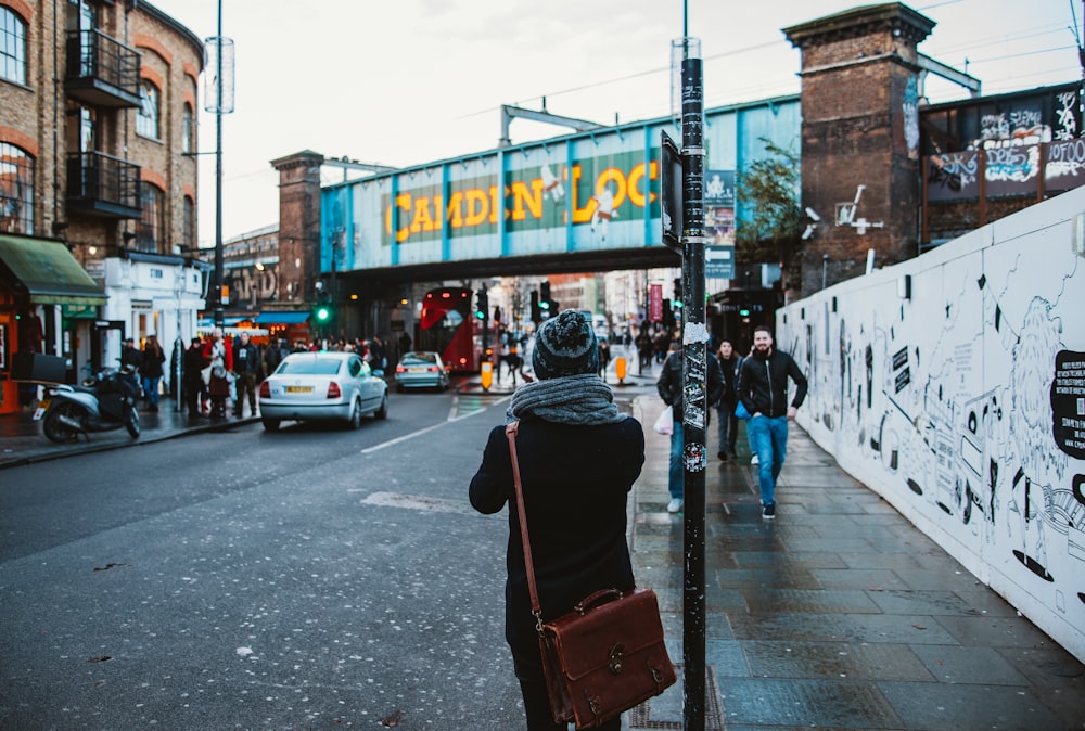 people walking on black concrete road beside buildings under white sky during daytime