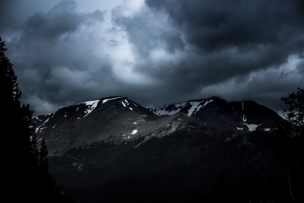 mountain range covered with snow under gray clouds