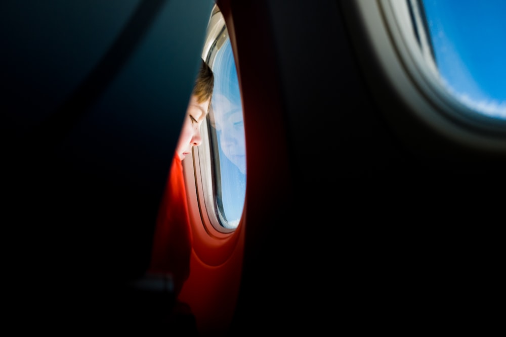 person looking at the window of an airplane