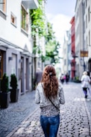 woman wearing gray top walking on sidewalk during daytime