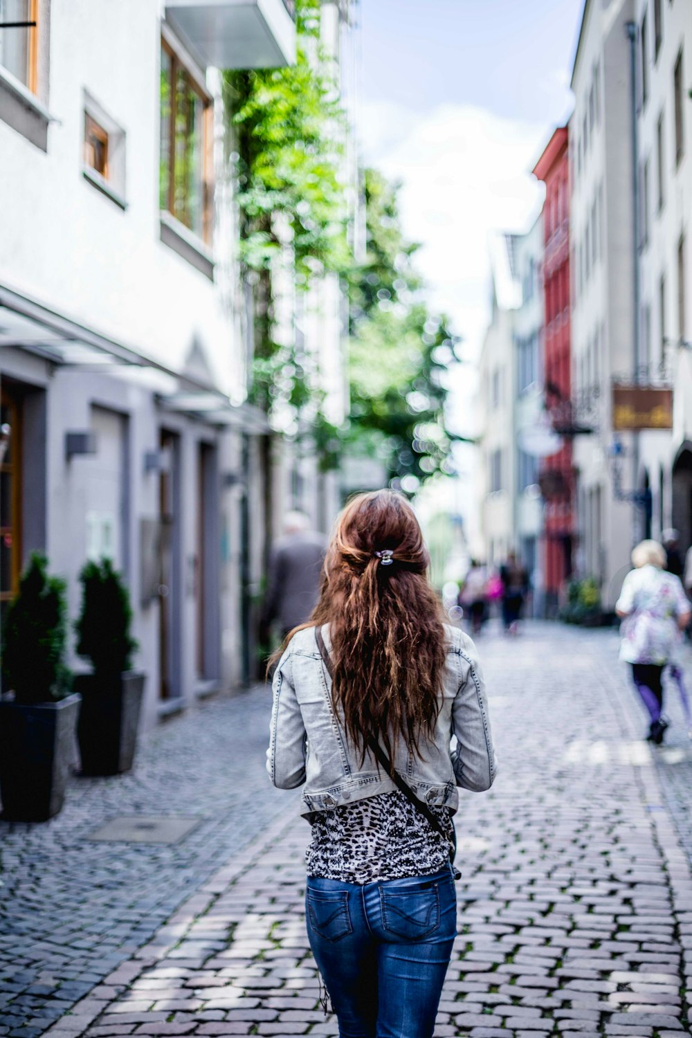 woman wearing gray top walking on sidewalk during daytime