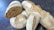 Several loaves of artisanal bread are scattered on a dark surface. The bread has a rustic appearance with a coated flour crust and varying shades of brown. One loaf is sliced open, revealing a dense, textured crumb.