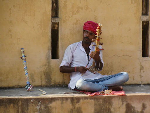 A serene Indian classical music teacher guiding a student with a sitar in a cozy room.