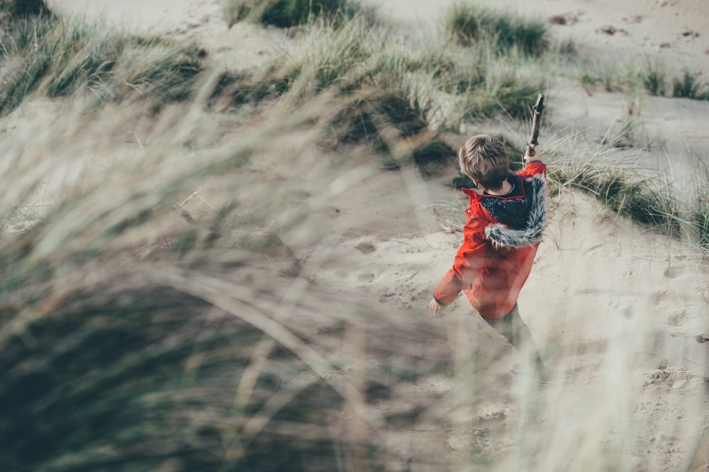 selective focus photo of person walking on gray sand with green grasses