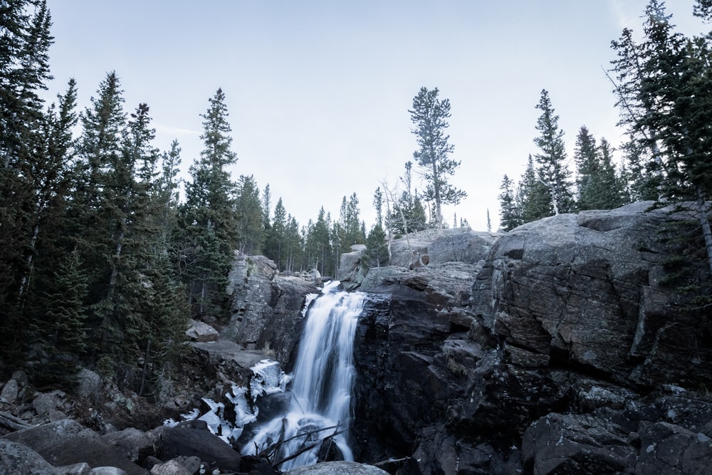 timelapse photography of waterfall surrounded by trees under blue sky at daytime