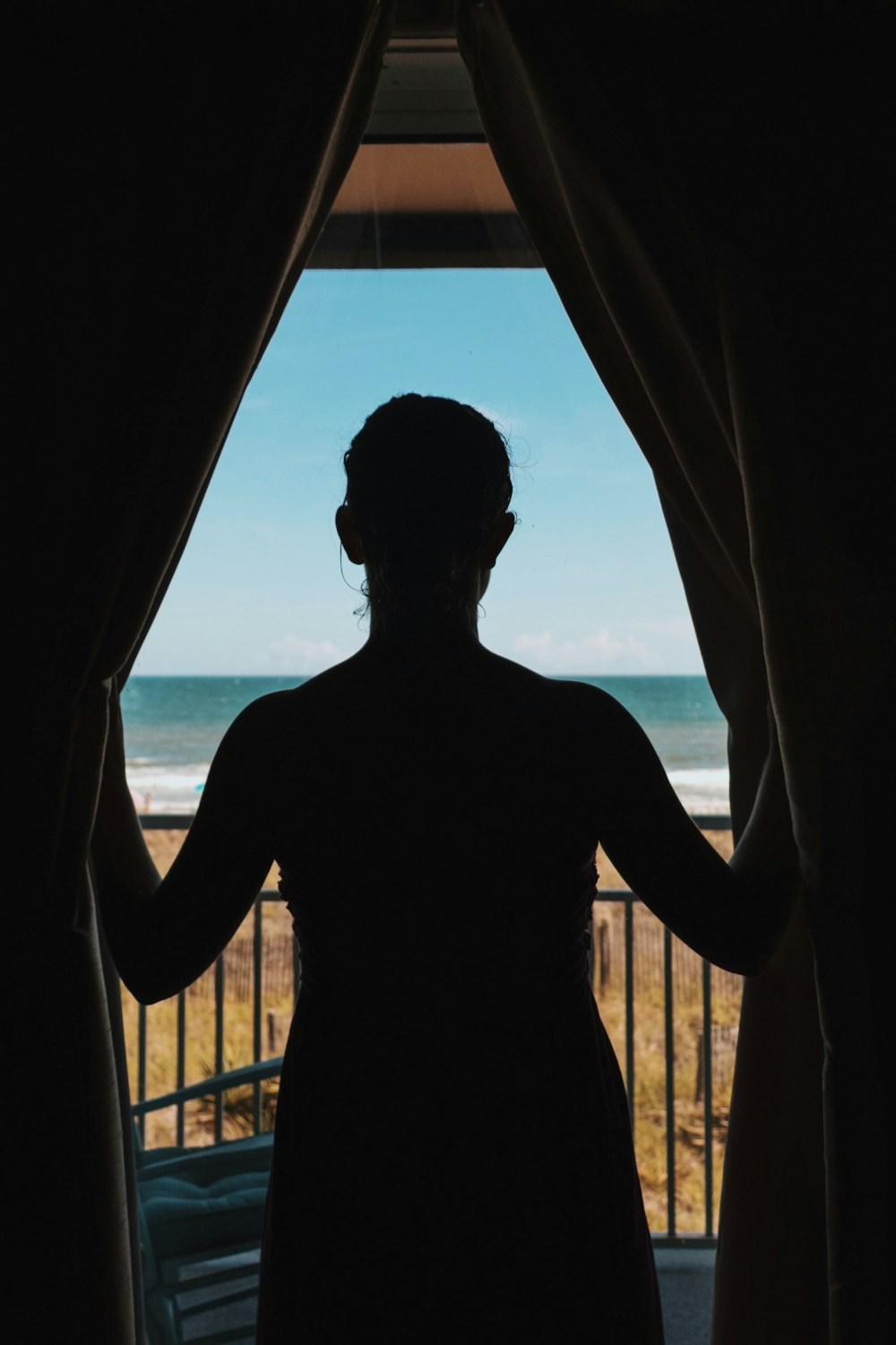 photo de silhouette de femme debout entre les rideaux