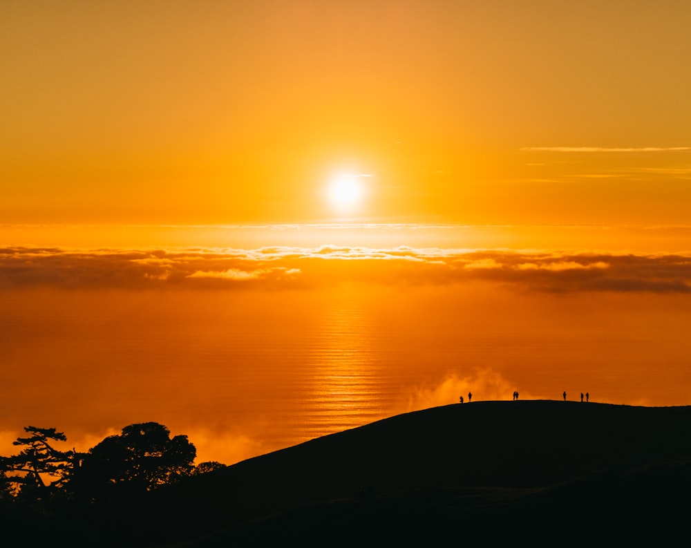 people on top of hill under white clouds golden hour photography