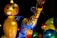 A collection of colorful, illuminated lanterns in the shapes of various animals and abstract figures, displayed against a dark background. The lanterns exhibit intricate patterns and vivid hues, creating a lively and festive atmosphere.