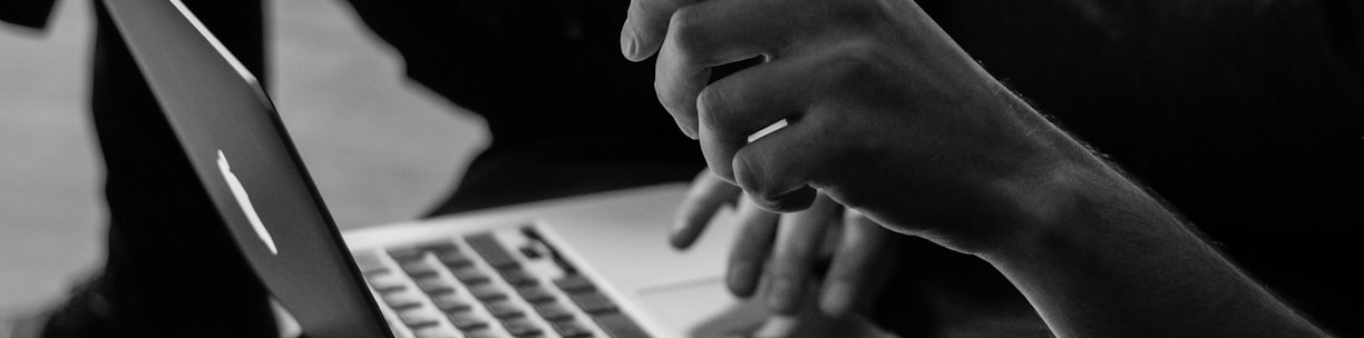 grayscale photo of person using MacBook